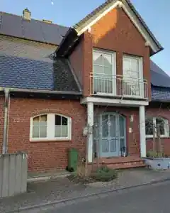 Photo of a brick house with a slate roof and front door under a clear sky