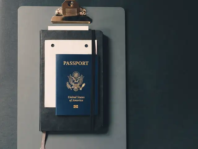 A passport and a blank card clipped to a clipboard on a dark desk